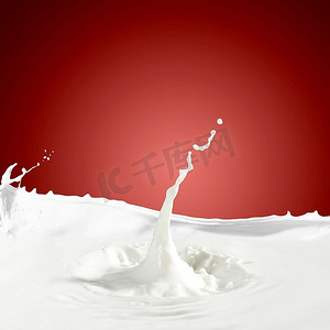 牛奶流动背景摄影照片_倒白色牛奶飞溅在彩色背景