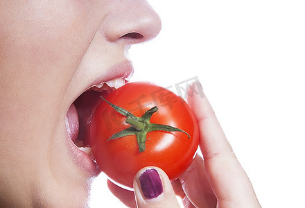 详细拍摄的年轻女子吃西红柿在白色背景