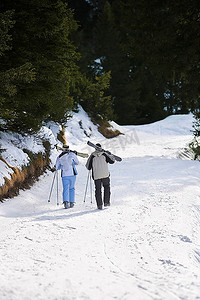 滑雪情侣背着滑雪板走下滑雪道后景俯瞰