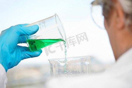 实验室技术员倾倒蓝绿色液体