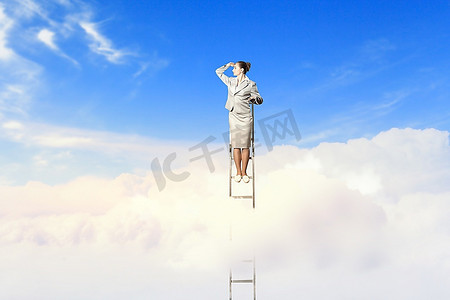 眺望远方人摄影照片_站在梯子上的女商人在多云的背景下眺望远方