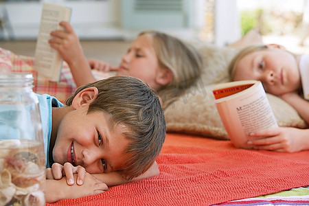 三个孩子(5-6，7-910-12)躺在户外的毯子上，专注于男孩