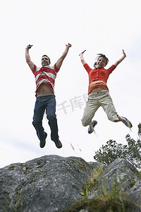 一对夫妇在岩石上举起手臂跳跃