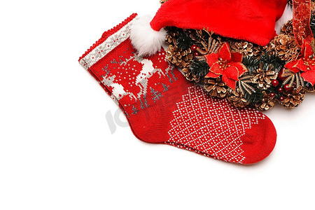 圣诞花环摄影照片_带圣诞帽的传统圣诞花环和白色隔开的袜子