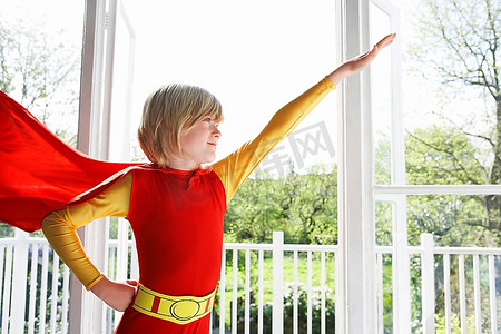 小男孩(7-9岁)穿着超级英雄服装手臂在室内举起的肖像