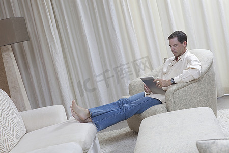 男人双脚朝上坐着看电子书