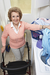 用洗衣机洗衣服的老年妇女