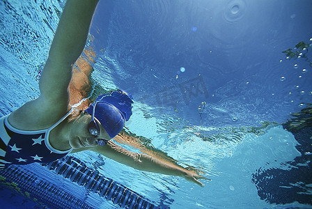 女游泳运动员穿着美国泳衣，在游泳池里游泳