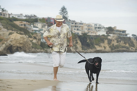 老年男子在海滩上遛狗