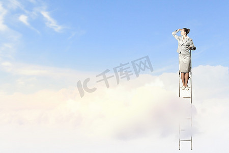 站在梯子上的女商人在多云的背景下眺望远方