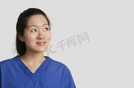 年轻的亚洲女医生抬头看着灰色的背景