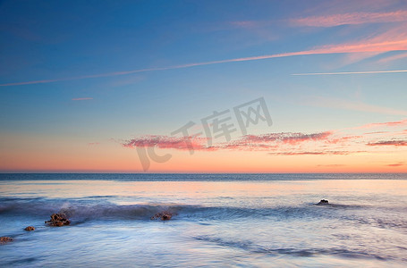 海洋摄影照片_海洋上令人惊叹的夏日落日，岩石和鲜艳的颜色