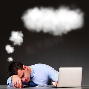 云彩气泡摄影照片_疲惫的商人睡在桌子边，头上顶着一片云彩，手里拿着笔记本电脑