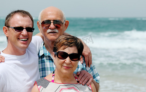 他在散步摄影照片_成人的儿子与他的父母在沙滩上散步