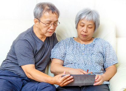 亚洲老年夫妇使用数字平板电脑