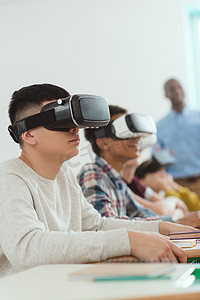 后面摄影照片_多民族高中生的侧面观使用虚拟现实耳机和教师站在后面