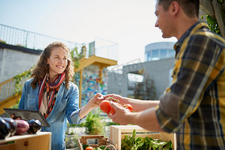 友好的女人抚育有机菜摊在农民市场和销售新鲜蔬菜从屋顶花园