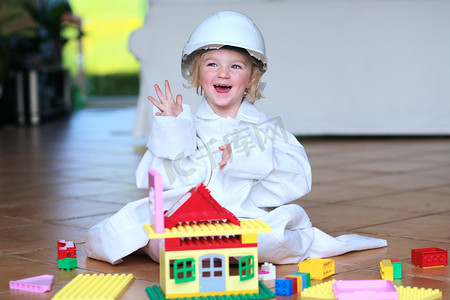 Toddler girl wearing safety helmet playing with building blocks