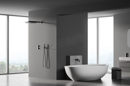 深灰色浴室，白色浴缸，靠窗淋浴，侧视图。大理石地板上现代木制灰色浴室的简约设计