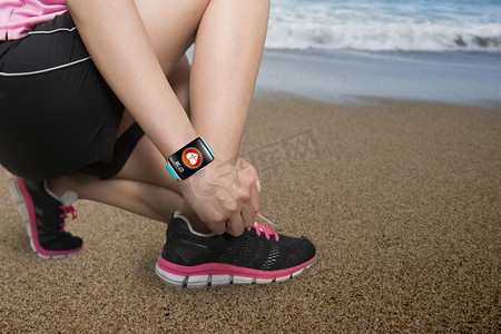 电子科技图标摄影照片_Sport woman tying shoelaces wearing health sensor smartwatch wit