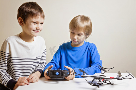 程序小摄影照片_孩子们玩无人机在家里。一个男孩抱着无线电遥控 fo quadcopter.