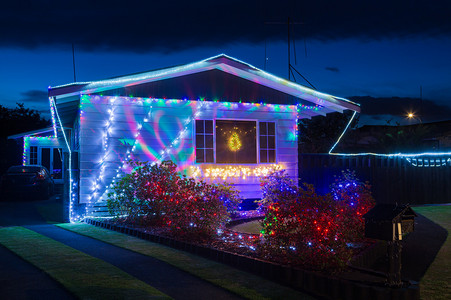 圣诞前夕的郊区房子，装饰着五彩缤纷的彩灯和投射在墙上的图案 