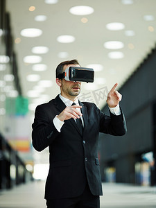 身着黑色西装的现代中年男子肖像和Vr眼镜点击虚拟现实中可视化的数据 