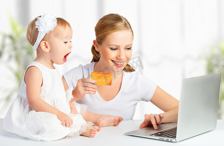妈妈和孩子元素摄影照片_母亲和婴儿的一台笔记本电脑和信用卡