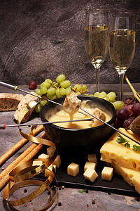 美食瑞士火锅晚餐在一个冬天的晚上, 与各种奶酪一起在一个板上的一个加热锅奶酪火锅与两个叉子蘸面包