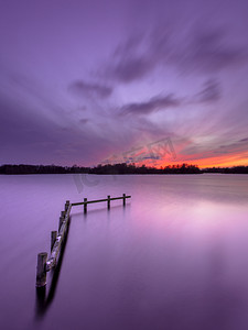 平静的湖面与木系泊邮政紫色落日