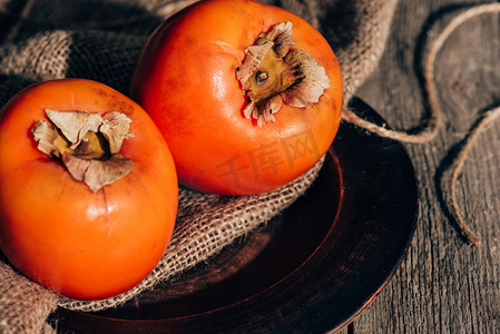 木桌上麻布上的两个熟柿子