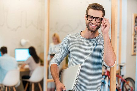 man carrying laptop and adjusting his eyeglasses