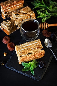 奶油和干果蛋糕。Medovik。蛋糕和一杯浓咖啡。蜂蜜蛋糕与干果 (干杏, 李子和坚果) 和浓咖啡在黑暗的背景。深色照片.