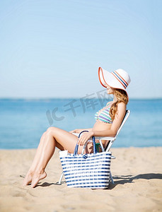 暑假和度假女孩坐在沙滩椅上晒日光浴
