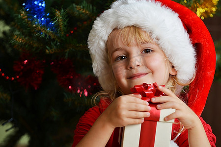 圣诞树附近戴着圣诞帽的漂亮小女孩