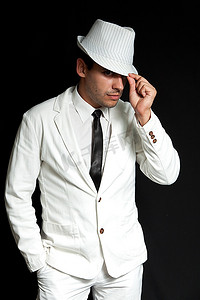 帽子快乐性感的年轻人。穿着白色西装和黑色领带。英俊的严肃的男人的肖像。一个从收集。