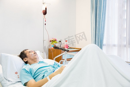 成熟资深人病人睡觉在医院病床与输血
