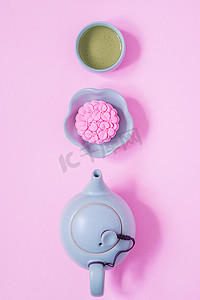 中秋灯笼灯笼摄影照片_粉红月饼，蓝色茶壶，粉红色背景上的绿茶。中国中秋节食品.