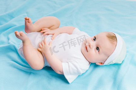 baby in hat lying on a blue blanket
