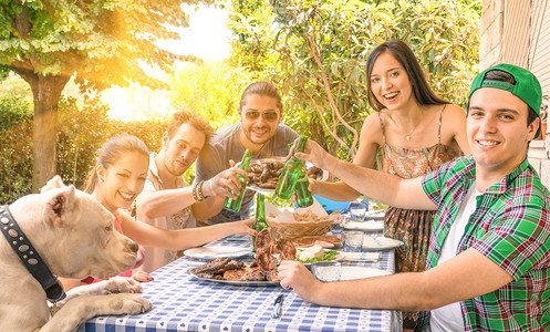 群快乐的朋友吃和在花园里烧烤-和年轻人在一起幸福的概念敬酒在家一起享受食物