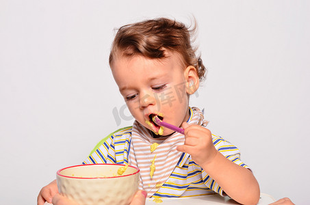 儿童baby摄影照片_Baby eating food with a spoon, toddler eating messy and getting