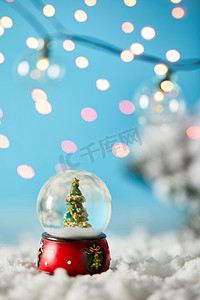 雪球中的圣诞树，站在蓝色的雪地上，灯光朦胧