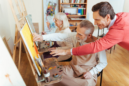 红色商务发展摄影照片_喜出望外的艺术家帮助老人在油画工作室