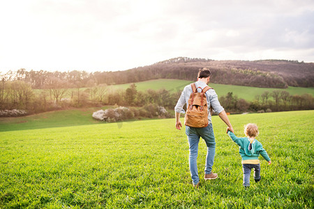 一个父亲与他的蹒跚学步的儿子在户外散步春天自然.