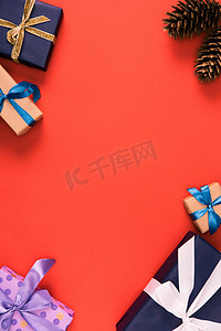 商务红色背景摄影照片_红色背景上的圣诞礼物和松树锥的顶部视图