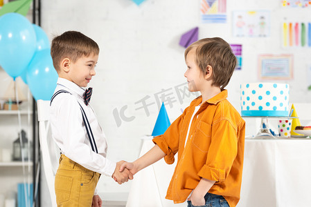 可爱的学龄前男孩在生日派对上握手