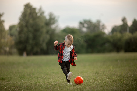 踢足球的小男孩摄影照片_一个带着狗踢足球的小男孩 