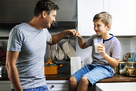 父子拳头在厨房里, 男孩拿着一杯牛奶