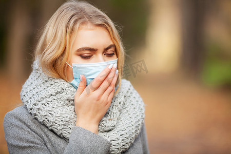 发烧温度摄影照片_感冒和流感。户外有医学面罩的妇女