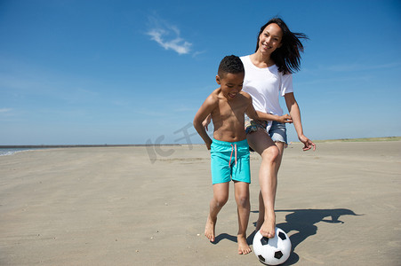 玩沙子摄影照片_面带笑容的母亲和儿子玩球